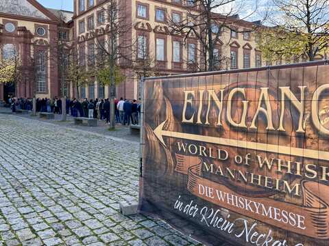 sehr lange Schlange von Menschen hinter dem Messe Plakat